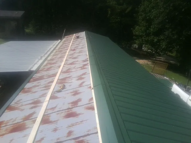 Old rusted panels beside newly installed green metal roofing — Wind Damage Roof Repair by Roofing Brothers in Johnsonville