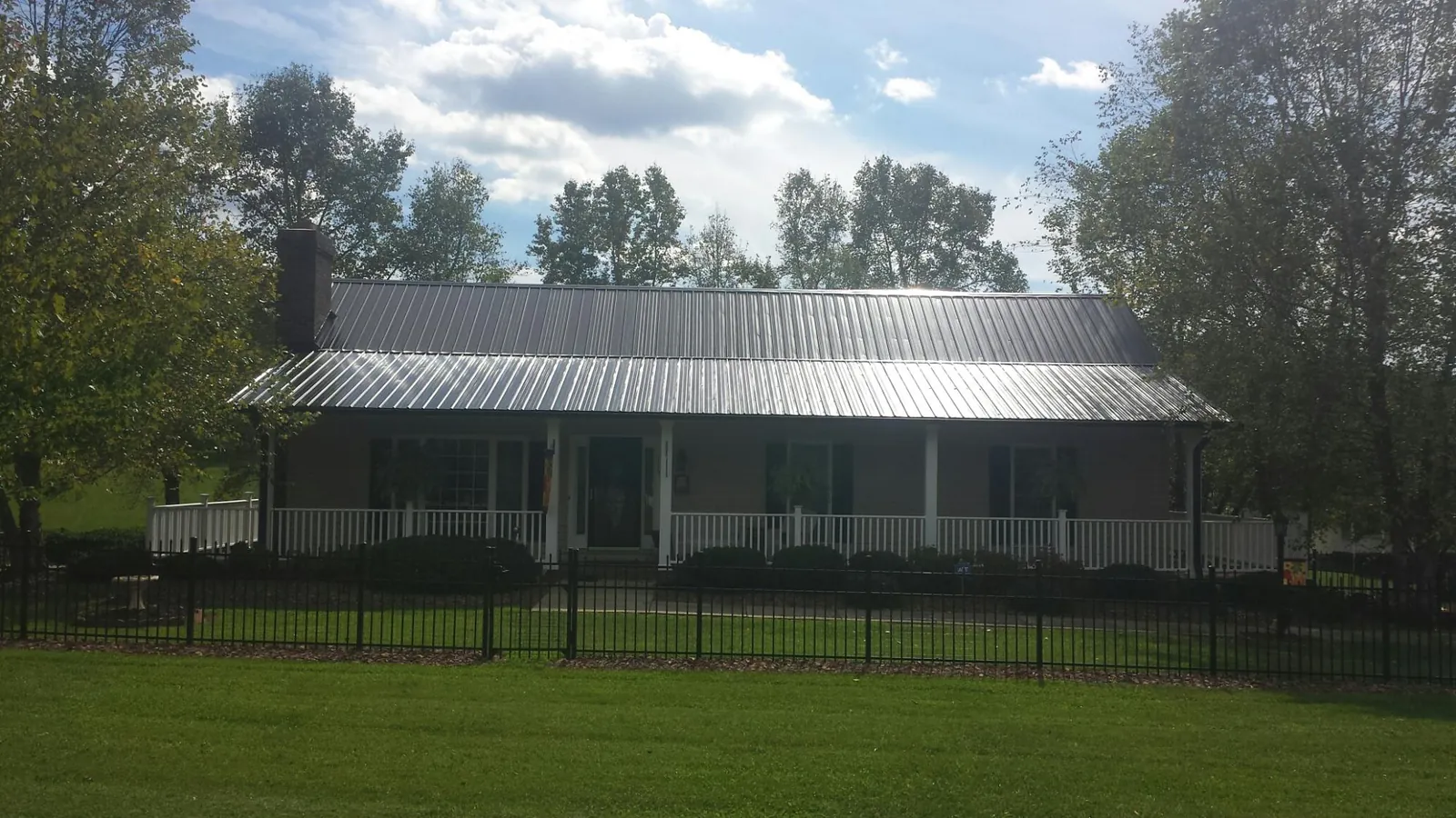 Gray metal roof on a brick ranch with a full width front porch — Gutter Guard Installation work by our crew in Johnsonville